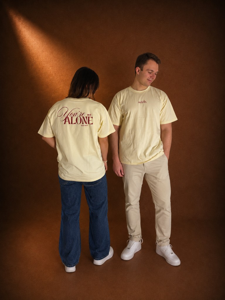 Cream Selah tee with "You're not alone" — Isaiah 41:10 printed on the back